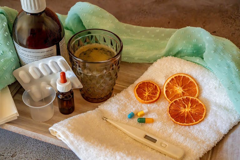 A collection of natural and medicinal cold remedies including tablets, a thermometer, and herbal drinks.